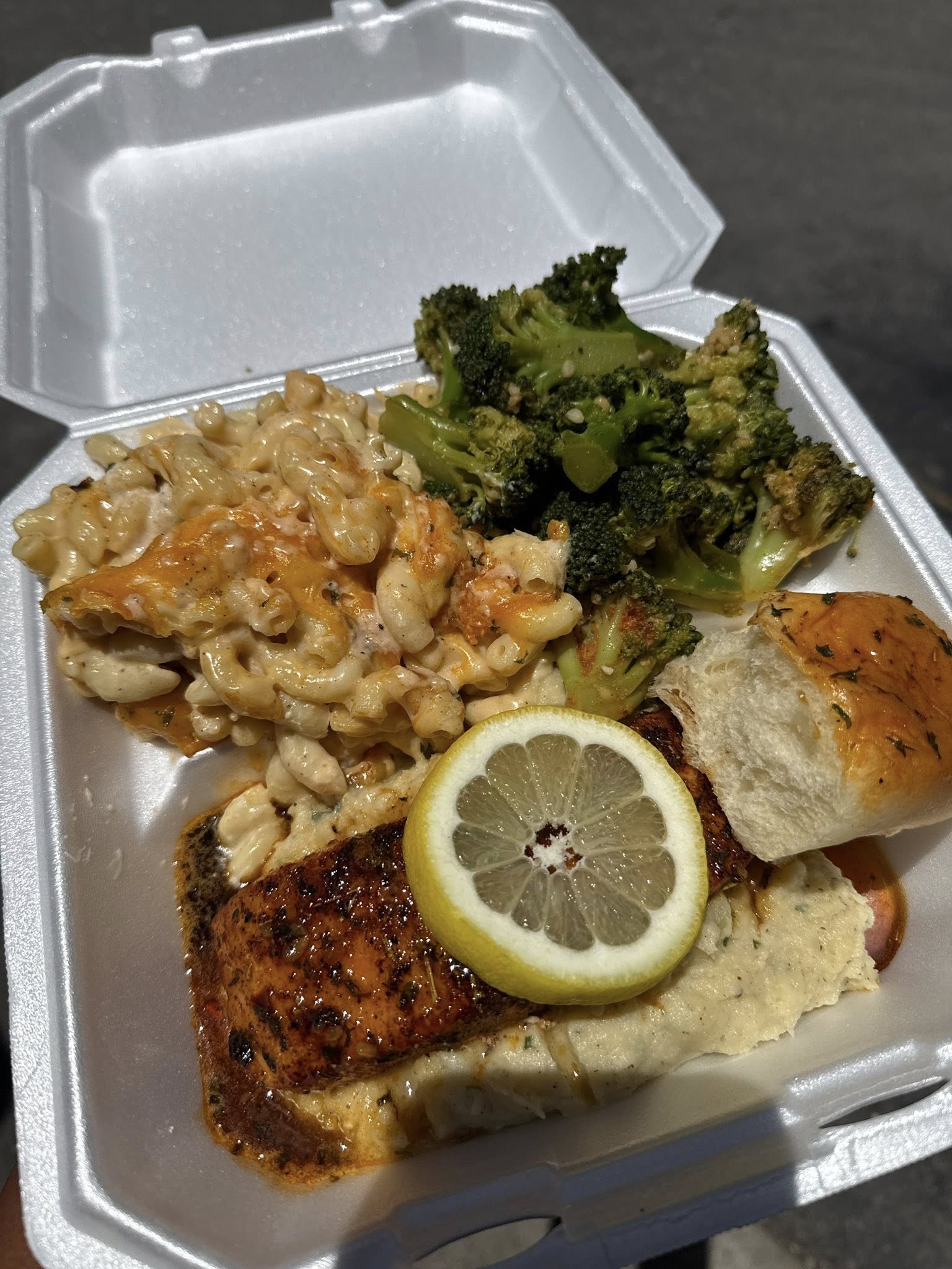 Blackened salmon fillet with a lemon wheel over garlic mashed potatoes, with baked mac and cheese, seasoned broccoli and a garlic roll