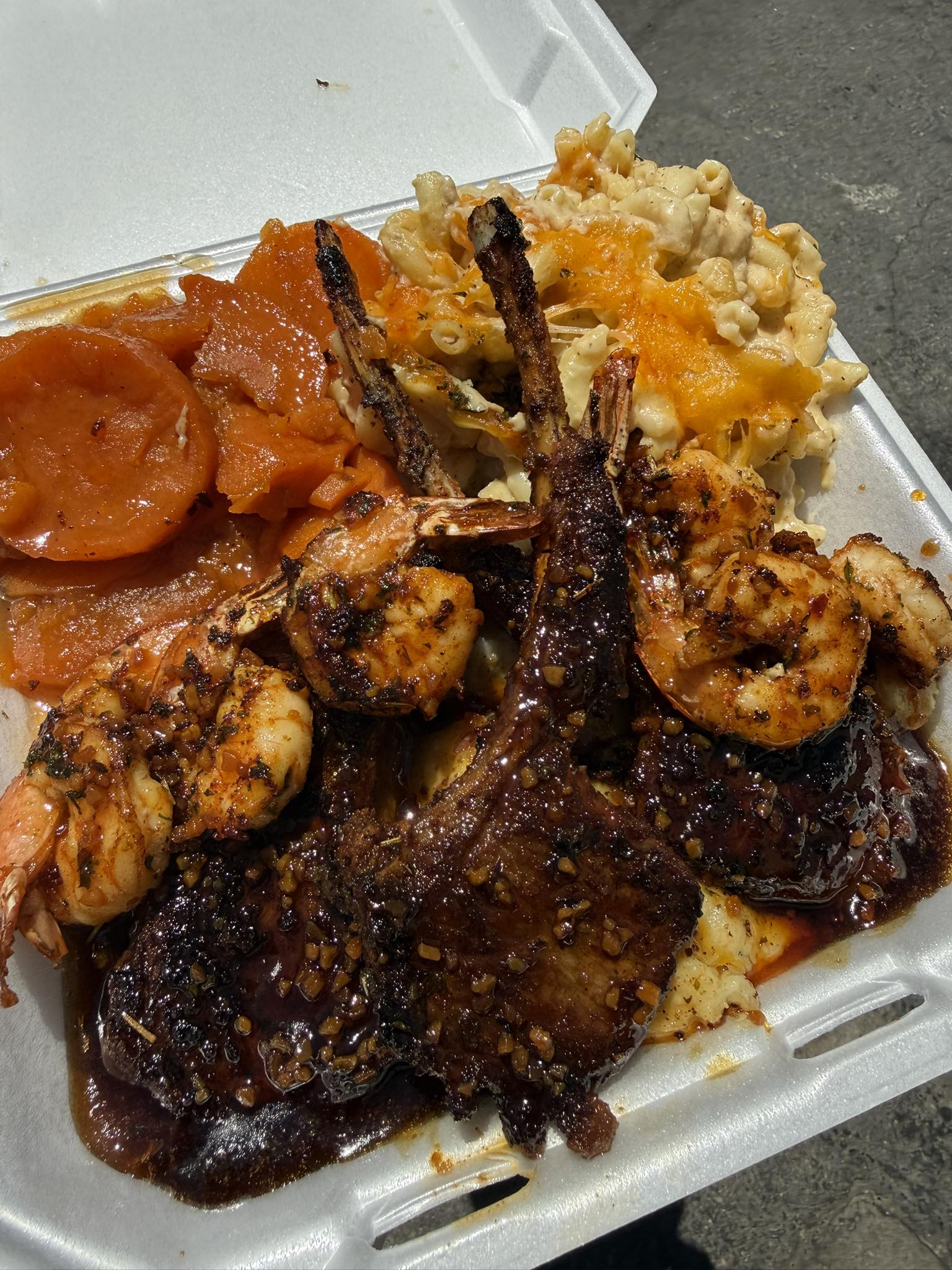 Grilled chops and seasoned shrimp plated with candied yams and baked mac and cheese