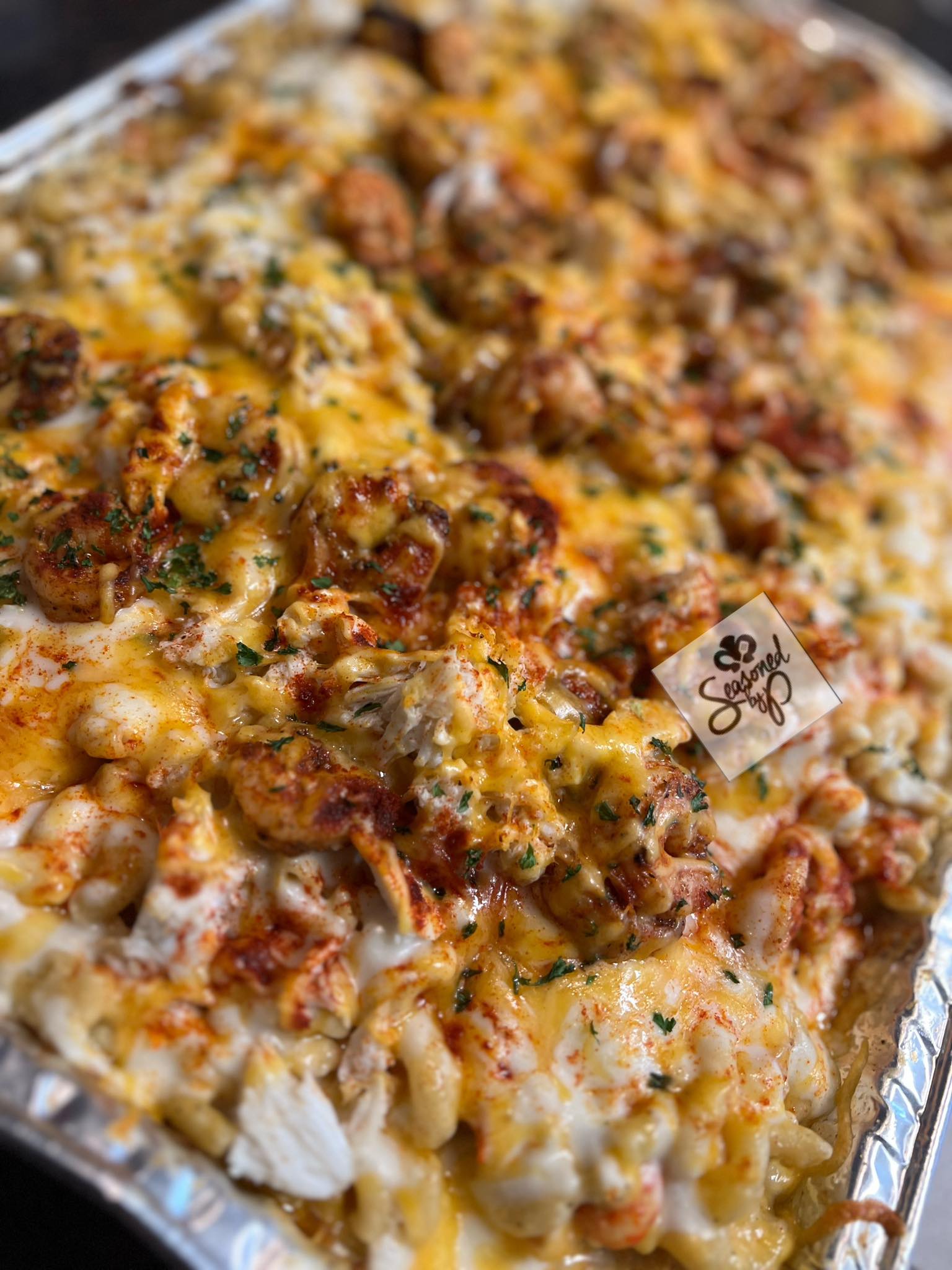 A full pan of baked seafood mac and cheese topped with shrimp, crab and melted cheddar