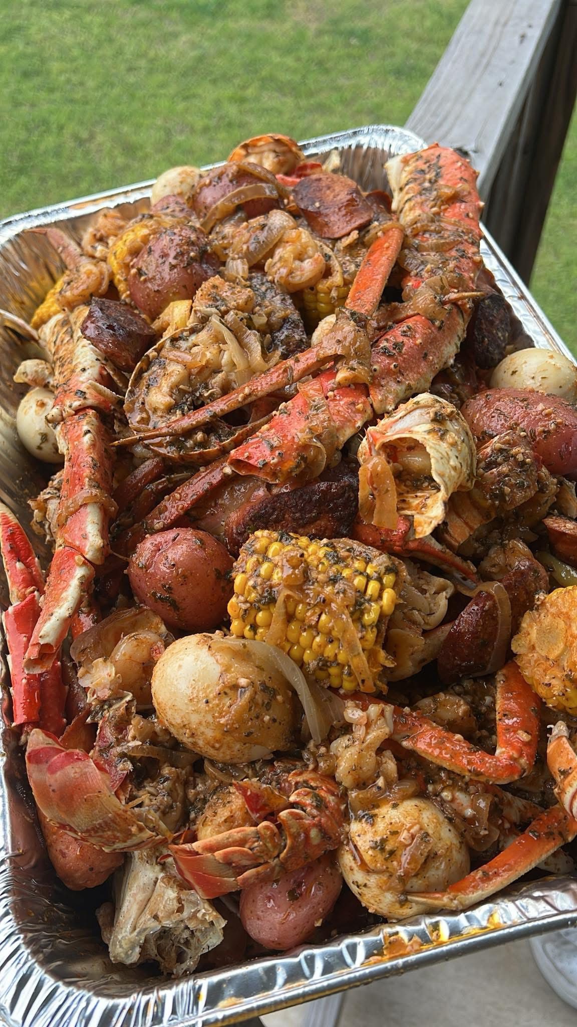 A foil pan seafood boil packed with crab legs, shrimp, smoked sausage, corn and red potatoes